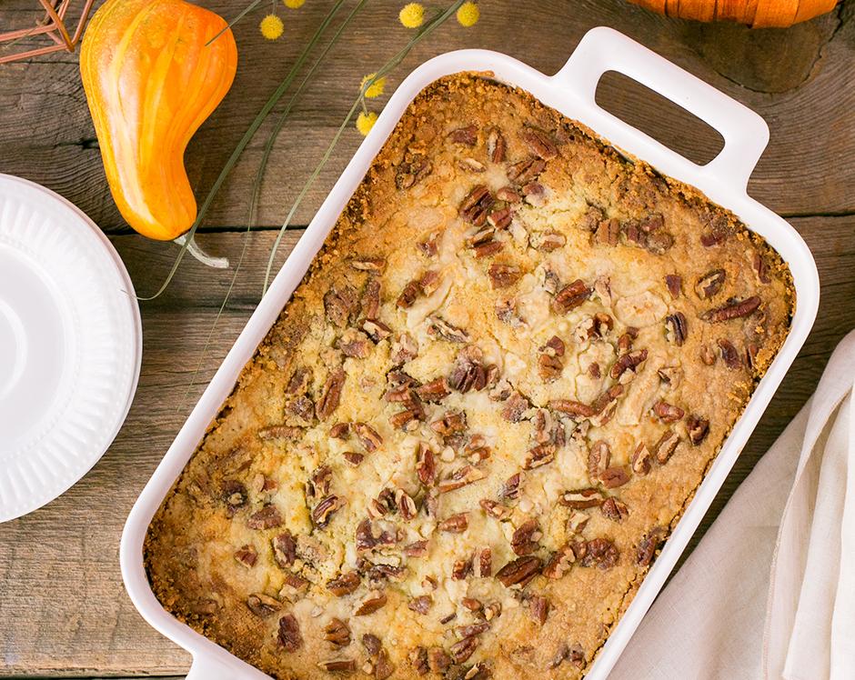 Pumpkin crunch cake made with Raven's Nest mulling spice topped with pecans surrounded by fall foliage and gourds