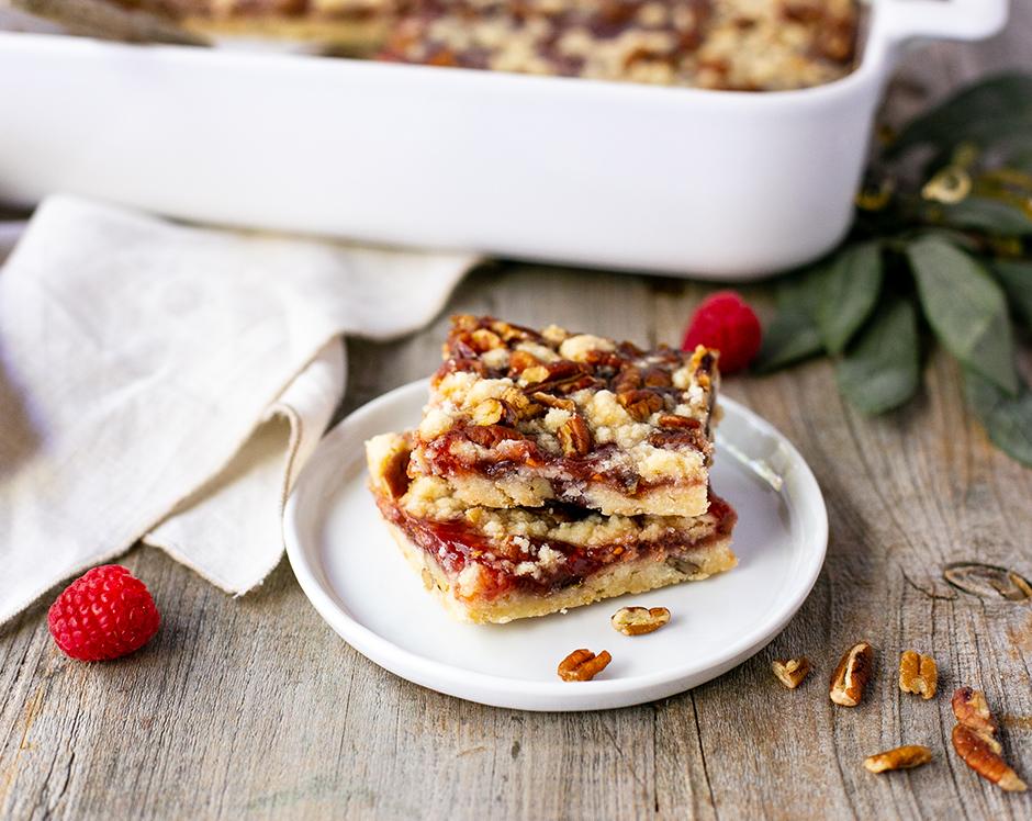 Raspberry pecan dessert bars made with Raven's Nest raspberry jalpaeno jam garnished with fresh pecans and raspberries